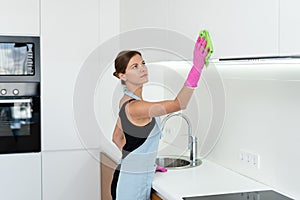 Young adult woman cleaning kitchen cabinet at home