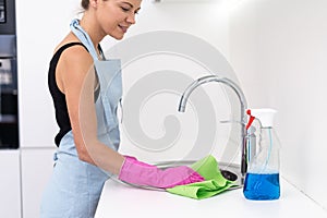 Young adult woman cleaning sink at kitchen