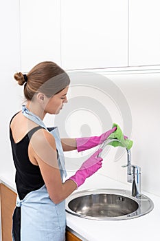 Young adult woman cleaning sink at kitchen