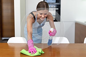 Young adult woman cleaning wooden surface with wipe