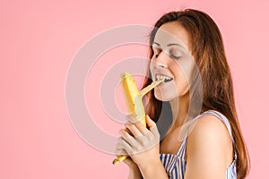 A young adult woman cleans the banana peel with her teeth, covering her eyes with pleasure. The concept of female erotic fantasies