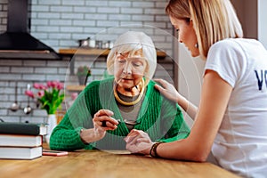 Young-adult woman comforting religious blue grey-haired woman in years