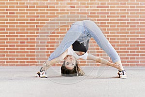 Young adult woman dancing stretching her body with head on the ground looking the camera