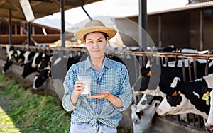 Young adult woman farmer working in cowshed