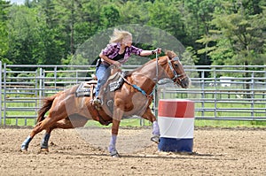 Young adult woman galloping around a turn in a barrel race