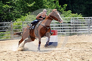 Young adult woman galloping through a turn in a barrel race