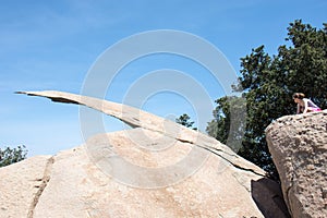 Young adult woman hiker attempts to get on top of Potato Chip Rock in Ramona California in San Diego