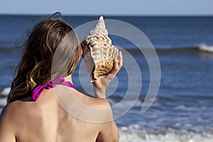 Young adult woman holding a triton seashell