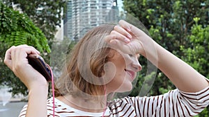 Young adult woman listen to music and dances emotionally in city park