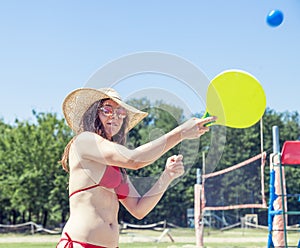 Young adult woman playing tennis on the beach