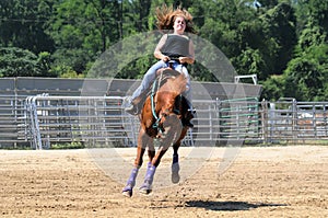 Young adult woman riding a bucking horse