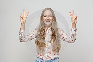 Young adult woman showing peace sign and toothy smiling