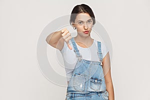 Young adult woman showing thumb down isolated on a gray background. .