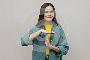 Young adult woman showing time out gesture, looking with nervous expression, deadline.