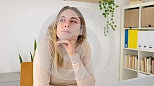 Young adult woman sitting at desk with laptop thinking about inspiration ideas