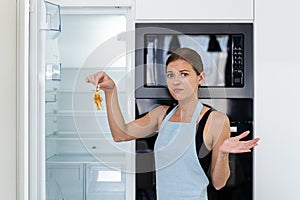 Young adult woman standing near refrigerator with apple