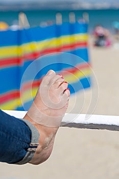 Young adult woman stretching legs on barrier at beach