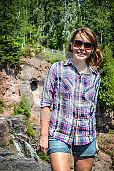 Young adult woman tourist hiker exploring Gooseberry Falls waterfall in Northern Minnesota