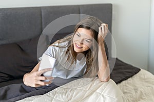 Young adult woman using smartphone in bed