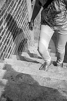 Young adult woman walking up the stairs and brick wall under con