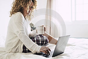 Young adult woman working at home in the bedroom during morning breakfast work activity - quarantine for coronavirus health photo