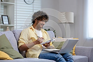 Young adult working from home with laptop and notebook