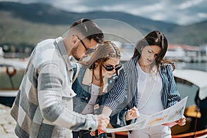 Young adults planning their journey with a map by the lakeside on a sunny day