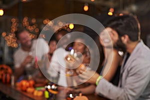 Young adults socialising at a party in a bar, defocussed