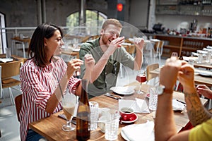 Young adults talking and smiling in restaurant. Conversation, friendship, lesure concept photo