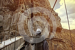 Young adventurous man with helmet crossing a wooden bridge