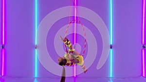 Young aerial acrobat girl rotates in the air on a hoop. Circus performer in a yellow leotard against the background of