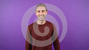 young affable long-haired guy showing hello gesture over isolated purple background 4K