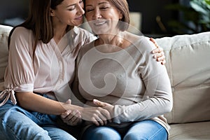 Young affectionate woman embracing happy middle aged mother.