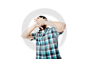 Young afraid man covering his face.