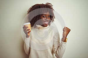 Young african afro woman holding cup of coffee standing over isolated white background screaming proud and celebrating victory and