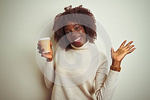 Young african afro woman holding cup of coffee standing over isolated white background very happy and excited, winner expression