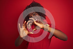 Young african afro woman wearing t-shirt standing over isolated red background smiling in love showing heart symbol and shape with