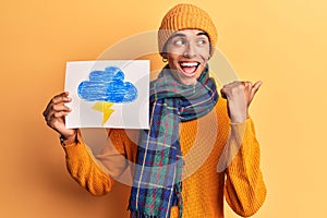 Young african amercian man holding thunder draw pointing thumb up to the side smiling happy with open mouth