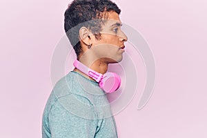 Young african amercian man listening to music using headphones looking to side, relax profile pose with natural face with