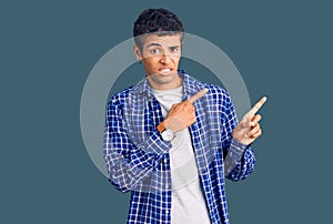 Young african amercian man wearing casual clothes pointing aside worried and nervous with both hands, concerned and surprised