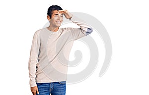 Young african amercian man wearing casual clothes very happy and smiling looking far away with hand over head