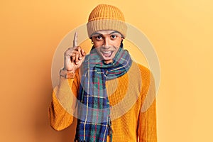 Young african amercian man wearing casual winter clothes pointing finger up with successful idea