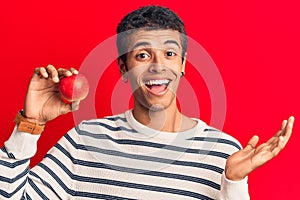 Young african amercian man wearing holding heart celebrating achievement with happy smile and winner expression with raised hand