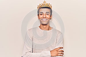 Young african amercian man wearing prince crown happy face smiling with crossed arms looking at the camera