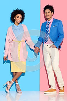 Young african amercian smiling girl and guy holding hands on pink and blue