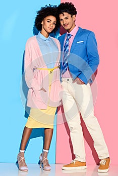 Young african amercian smiling girl and guy hugging on pink and blue