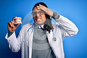 Young african american afro dentist doctor man wearing stethoscope holding teeth stressed with hand on head, shocked with shame