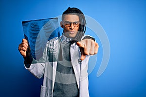 Young african american afro doctor man with dreadlocks holding chest lung xray pointing with finger to the camera and to you, hand