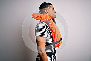 Young african american afro man with dreadlocks wearing orange lifejacket looking to side, relax profile pose with natural face