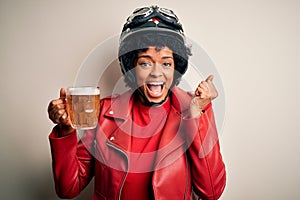 Young African American afro motorcyclist woman with curly hair drinking jar of beer screaming proud and celebrating victory and